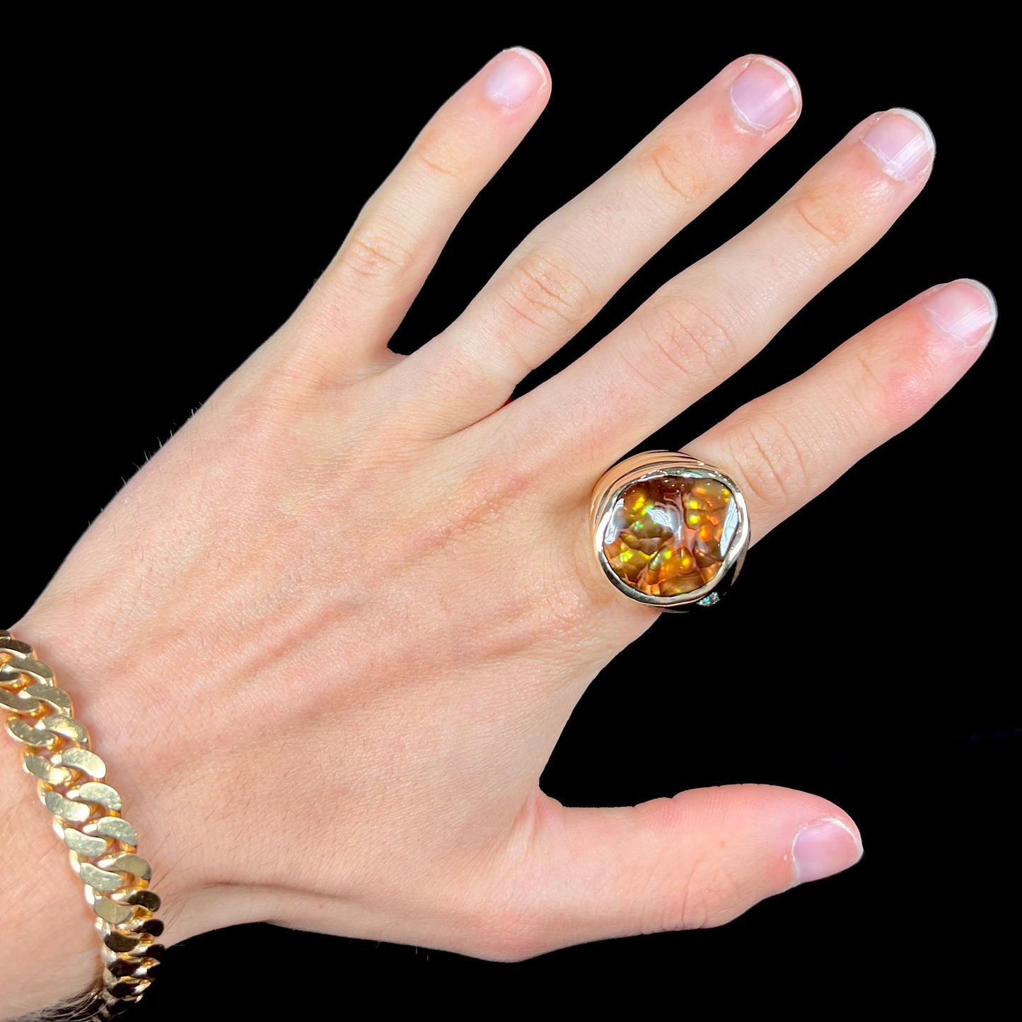 A men's heavy yellow gold ring set with a Mexican fire agate stone and three round brilliant cut diamond accents.