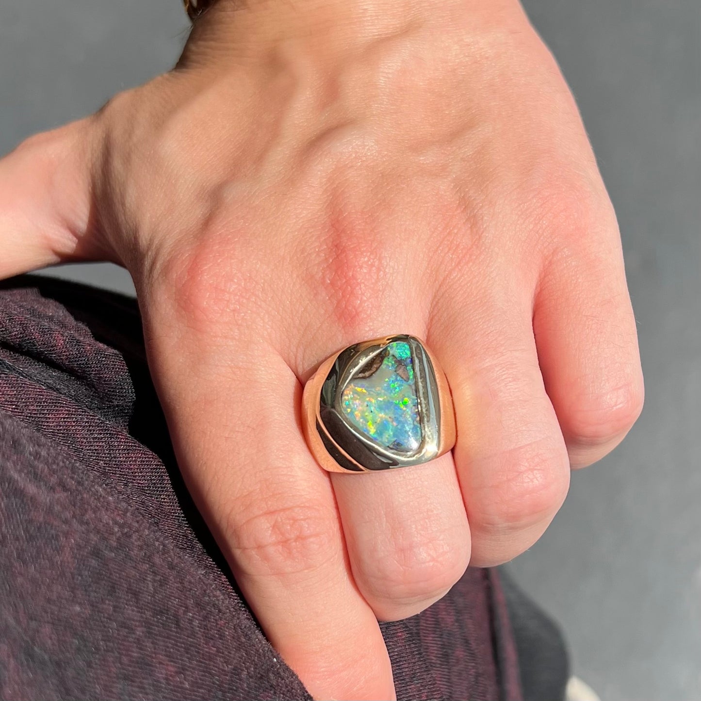 A men's yellow gold solitaire ring set with a triangular shaped natural boulder opal.