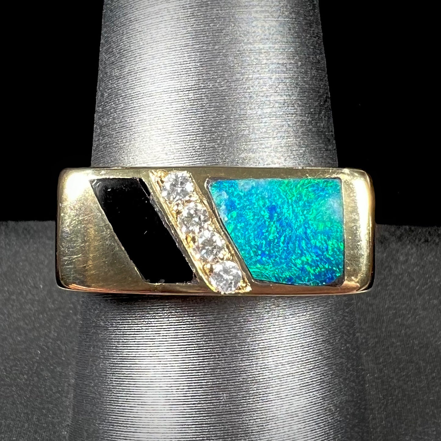 A men's yellow gold ring inlay set with onyx, natural black opal, and four diamonds.