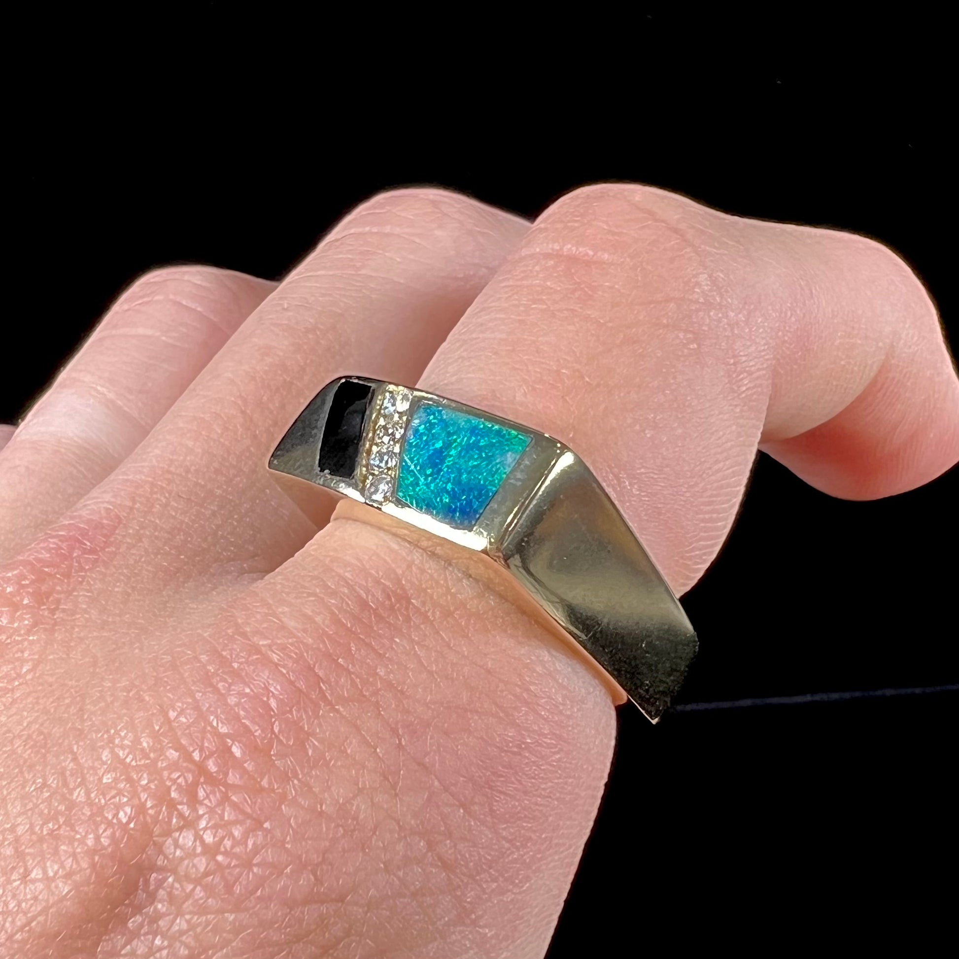 A men's yellow gold ring inlay set with onyx, natural black opal, and four diamonds.