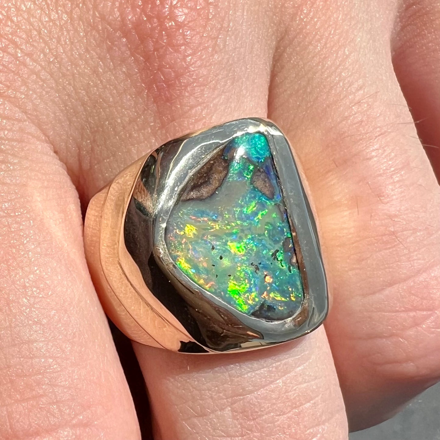 A men's yellow gold solitaire ring set with a triangular shaped natural boulder opal.