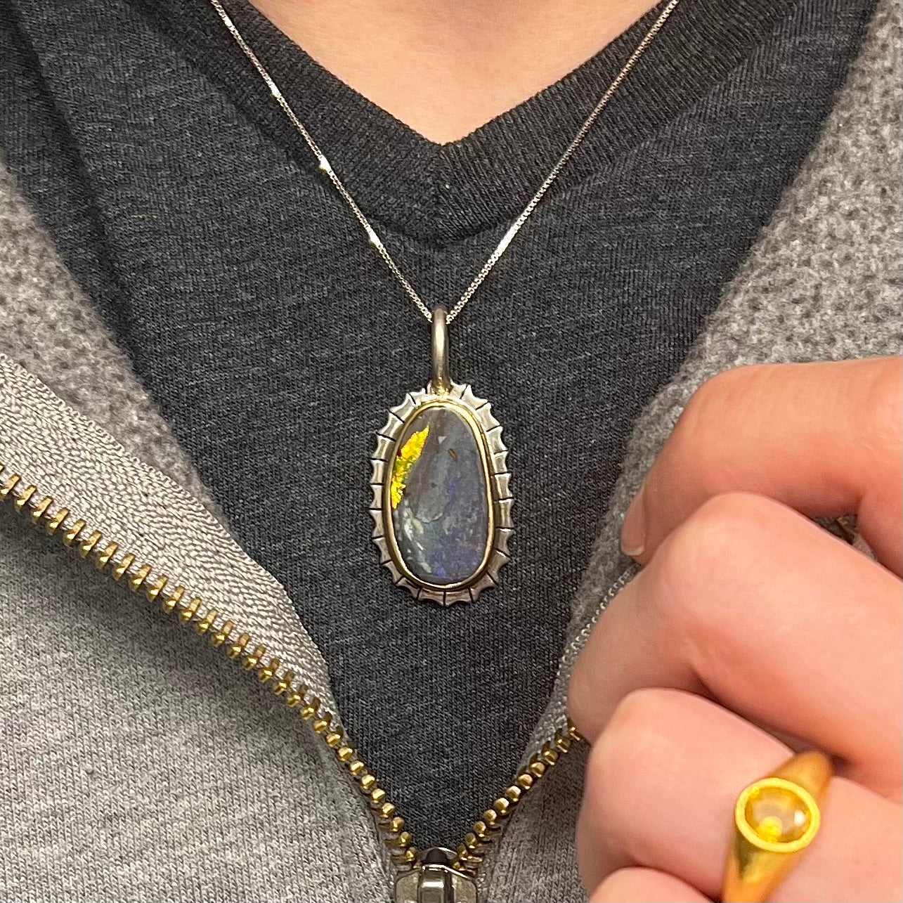 A Southwest style two-tone sterling silver pendant set with a black boulder opal with a yellow gold bezel.
