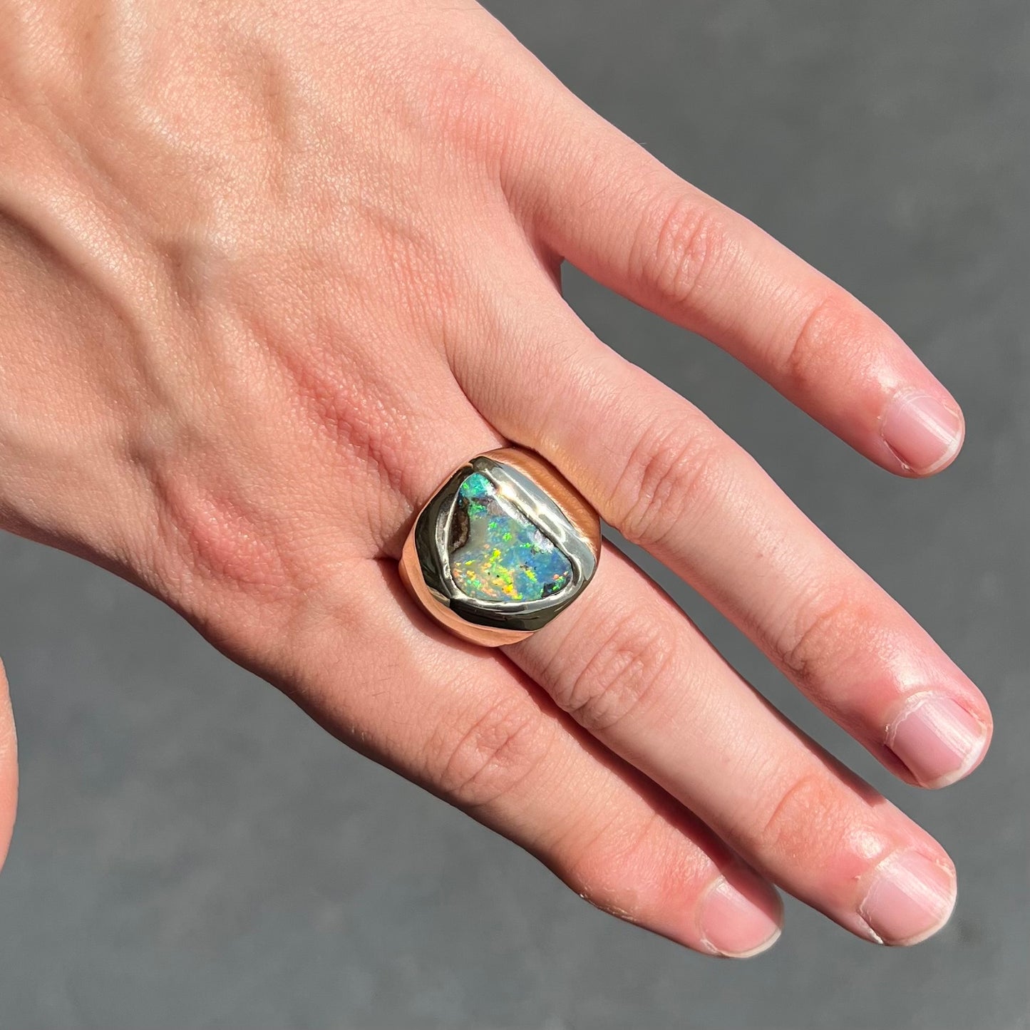 A men's yellow gold solitaire ring set with a triangular shaped natural boulder opal.