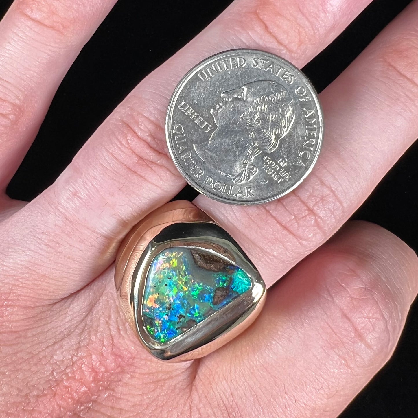 A men's yellow gold solitaire ring set with a triangular shaped natural boulder opal.