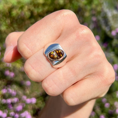 A unisex sterling silver solitaire ring bezel-set with a freeform Mexican fire agate cabochon.  The stone is green and pink.