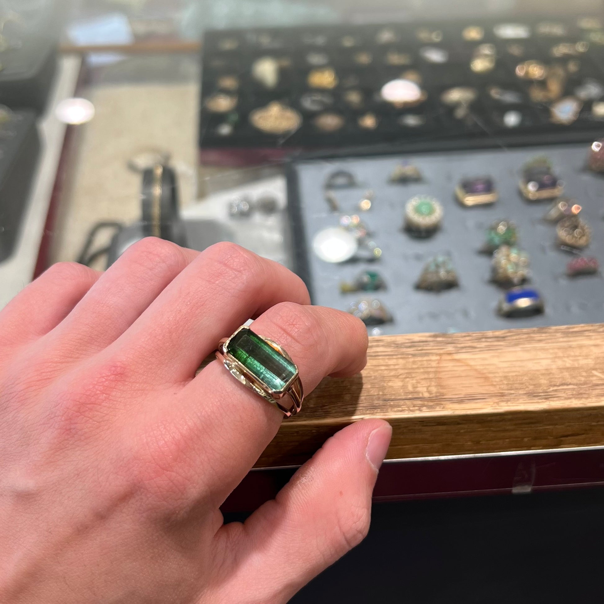 A men's emerald cut tricolor tourmaline solitaire ring in yellow gold.  The tourmaline shifts from green to blue green to blue.