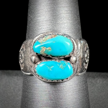 A unisex sterling silver ring bezel set with two Pilot Mountain turquoise stones.  The ring is stamped with sun patterns.