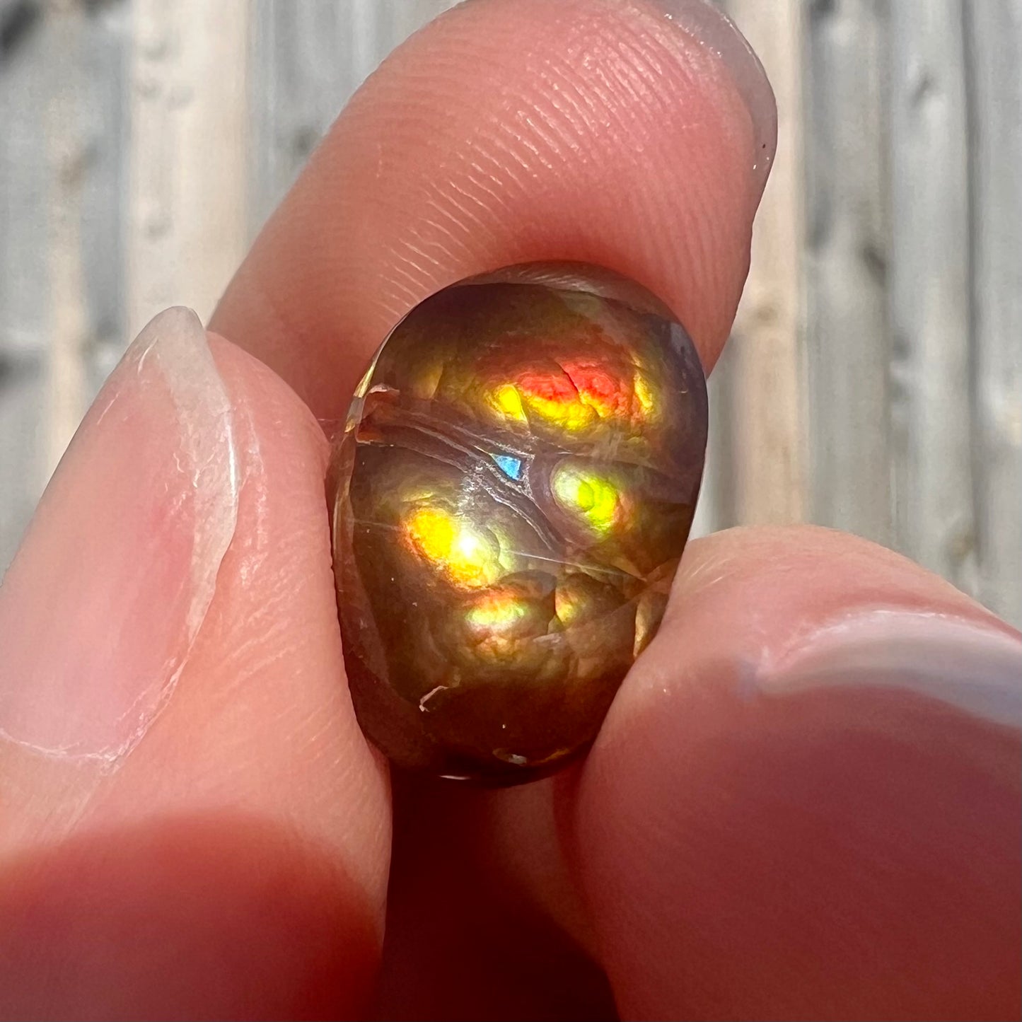 A loose Mexican fire agate cabochon.  The stone has a bright purple and blue iris pattern.