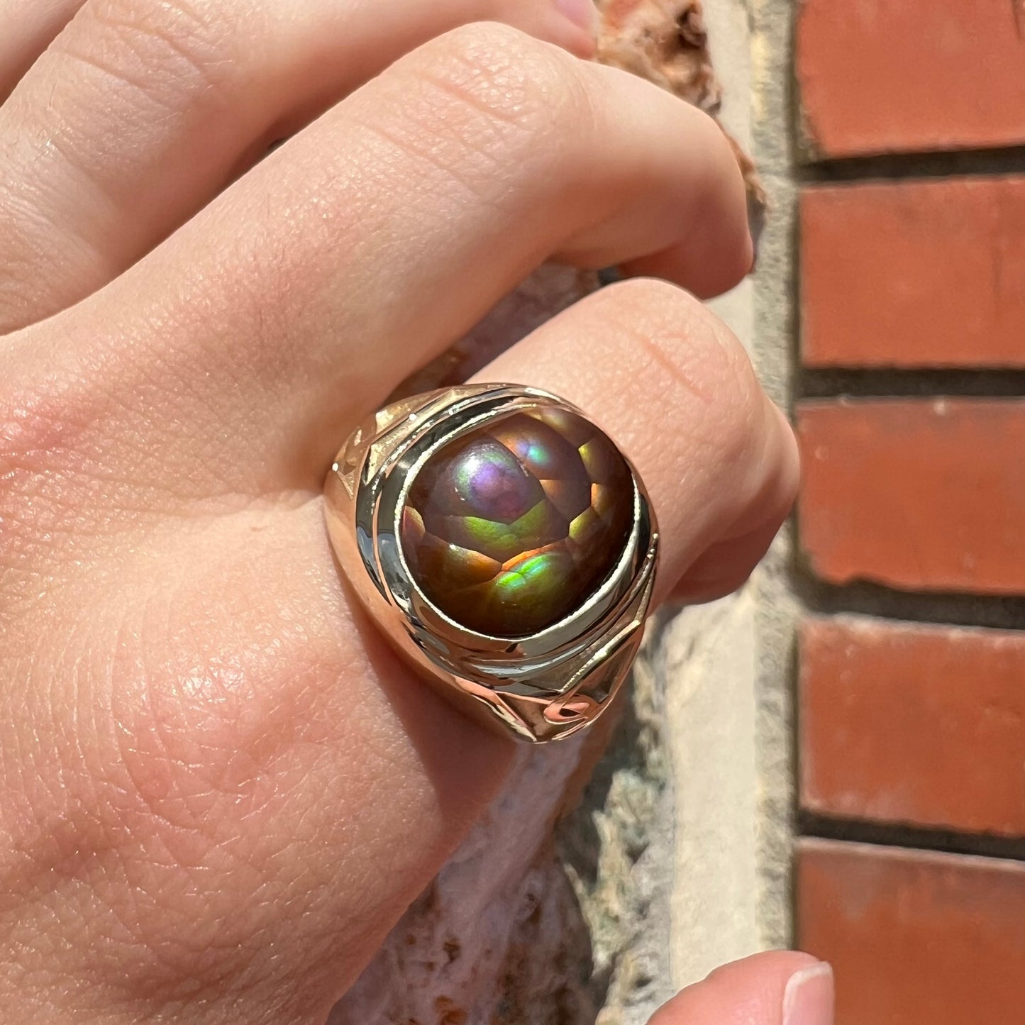 A men's solid yellow gold ring set with a Mexican fire agate stone.  The fire agate has a puple bull's eye pattern.