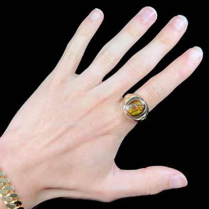 A men's solid yellow gold ring set with a Mexican fire agate stone.  The fire agate has a puple bull's eye pattern.
