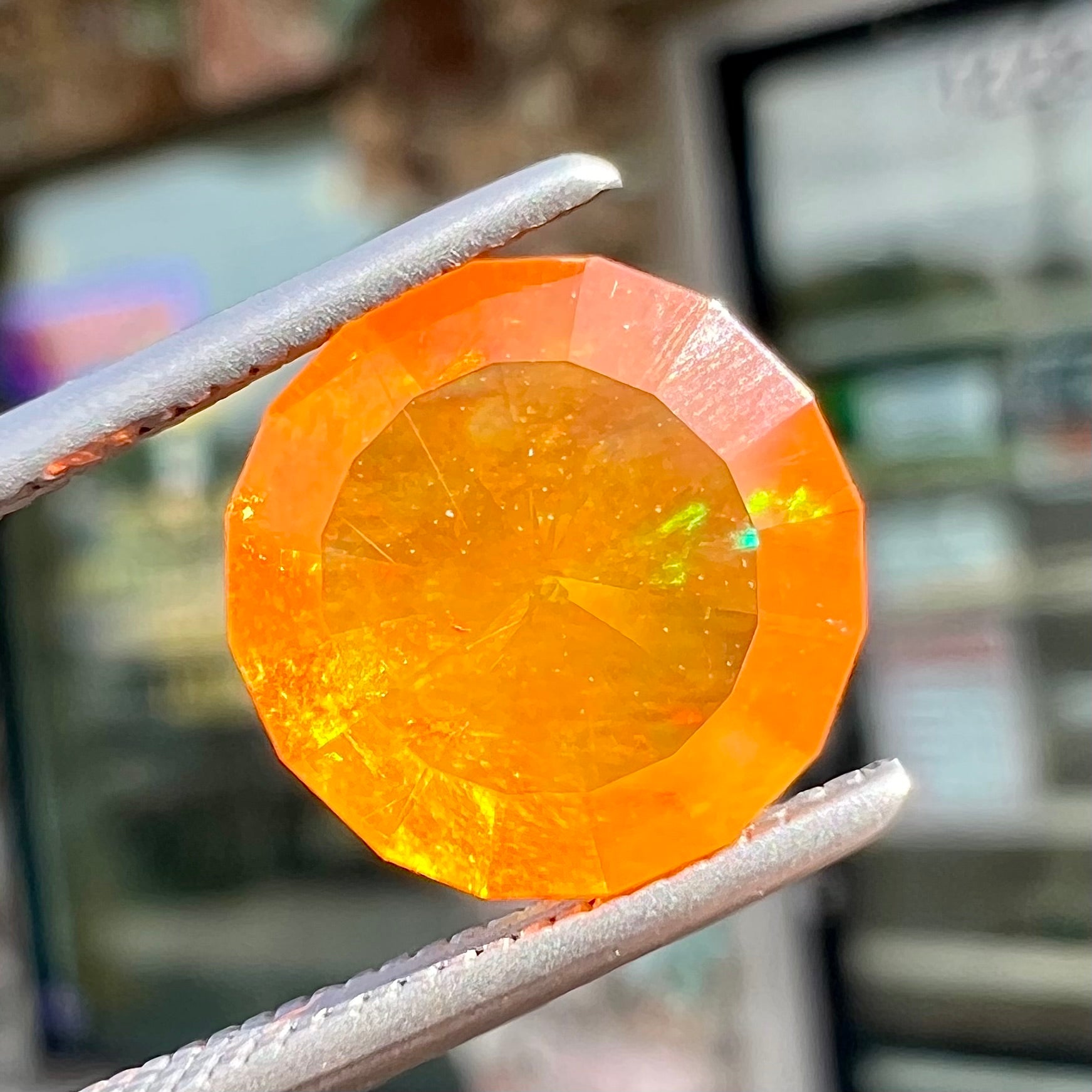 A loose, round faceted cut fire opal from Mexico.  The body color is yellowish orange with red, green, and yellow fire.