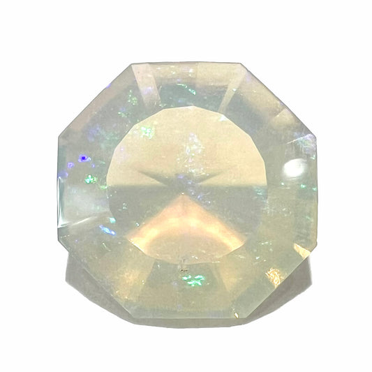 A loose, faceted octagon cut Mexican fire opal gemstone.  The stone is a light yellow color with blue and green fire.