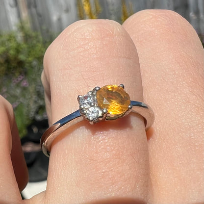 A ladies' sterling silver ring set with a Mexican fire opal and round white zircon stones.