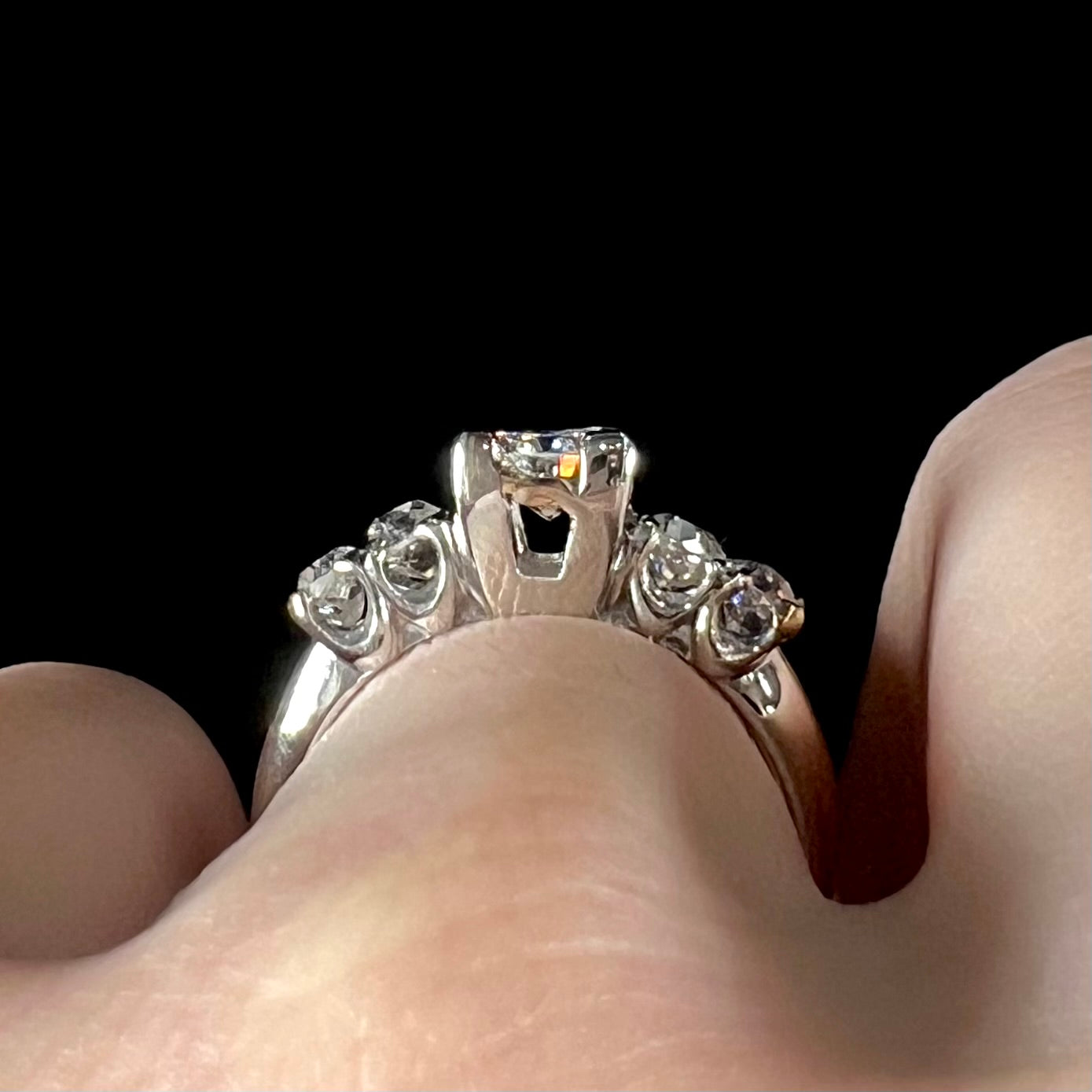 A ladies' 1800's antique white gold diamond ring.  The center stone is an Early American Cut diamond, and the accent stones are Old Mine Cut diamonds.