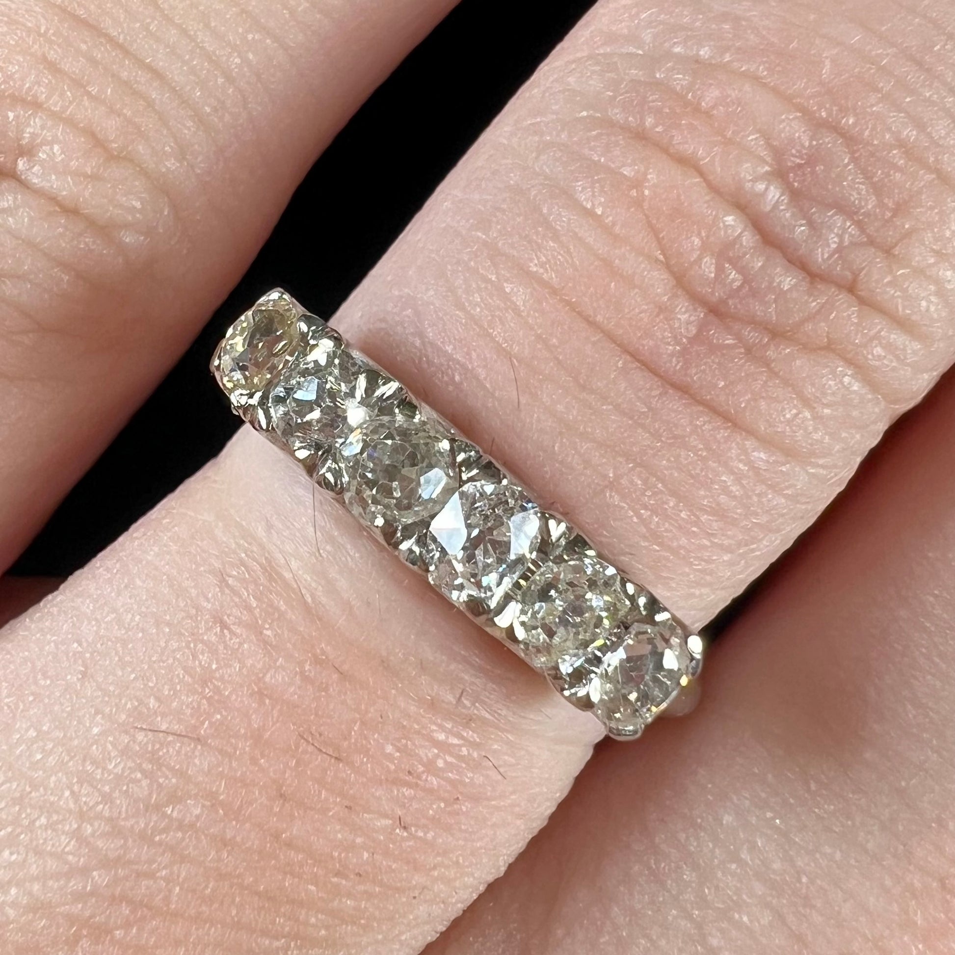 An antique white gold diamond wedding band set with six old mine cut natural diamonds.