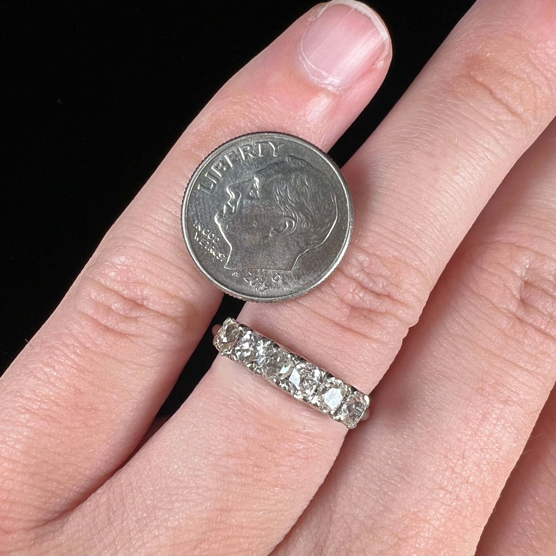An antique white gold diamond wedding band set with six old mine cut natural diamonds.