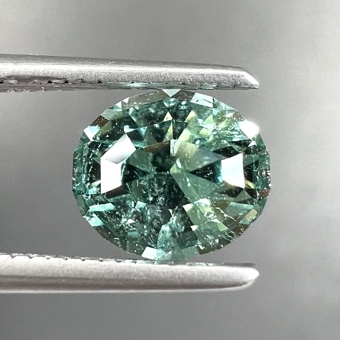 A loose, faceted modified oval cut mint green tourmaline gemstone.