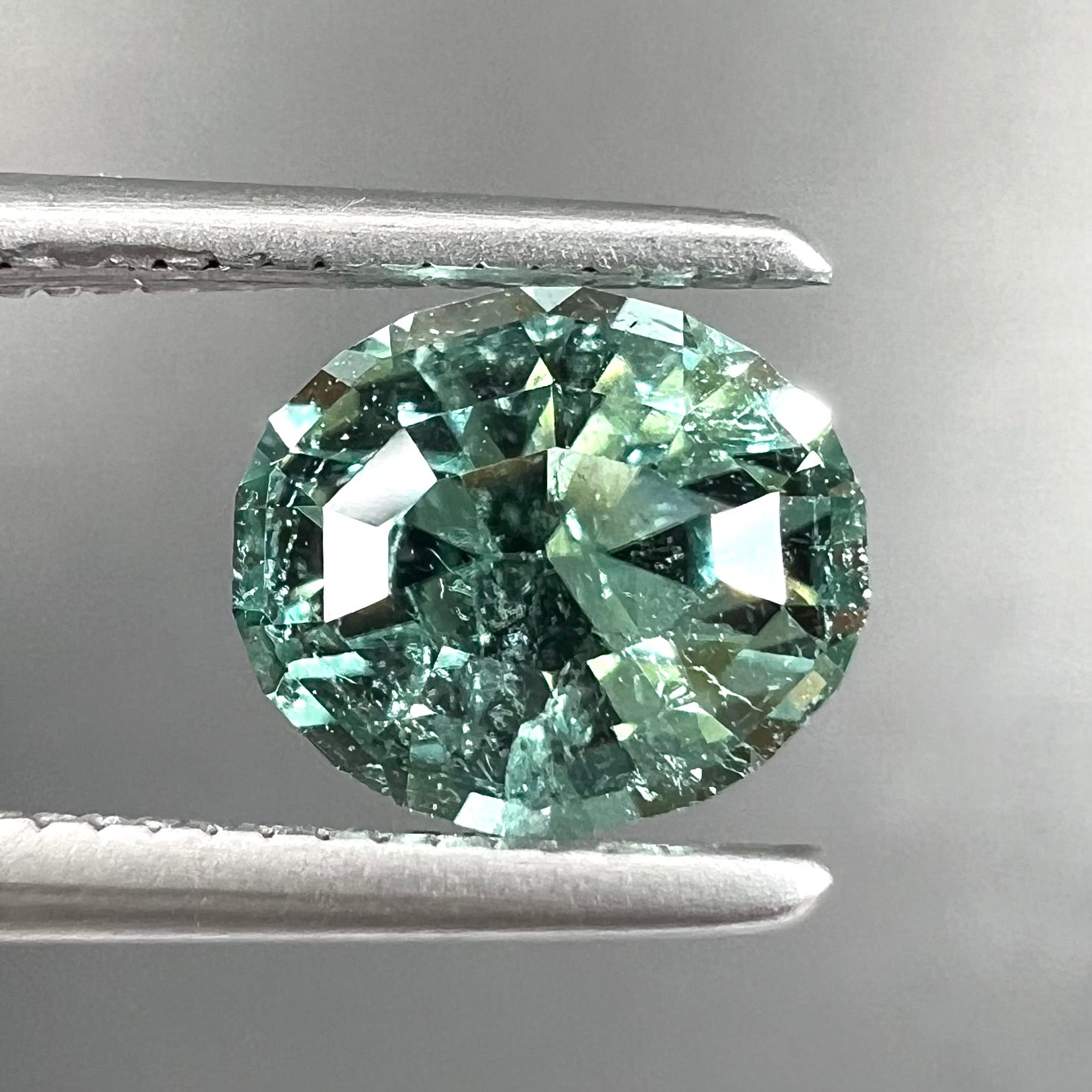 A loose, faceted modified oval cut mint green tourmaline gemstone.