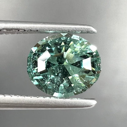 A loose, faceted modified oval cut mint green tourmaline gemstone.