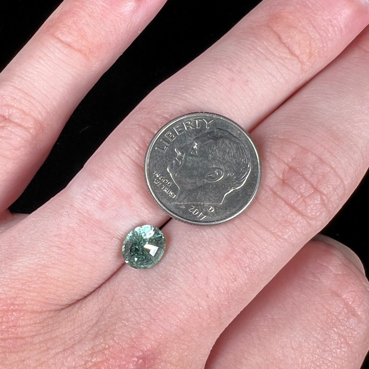 A loose, faceted modified oval cut mint green tourmaline gemstone.