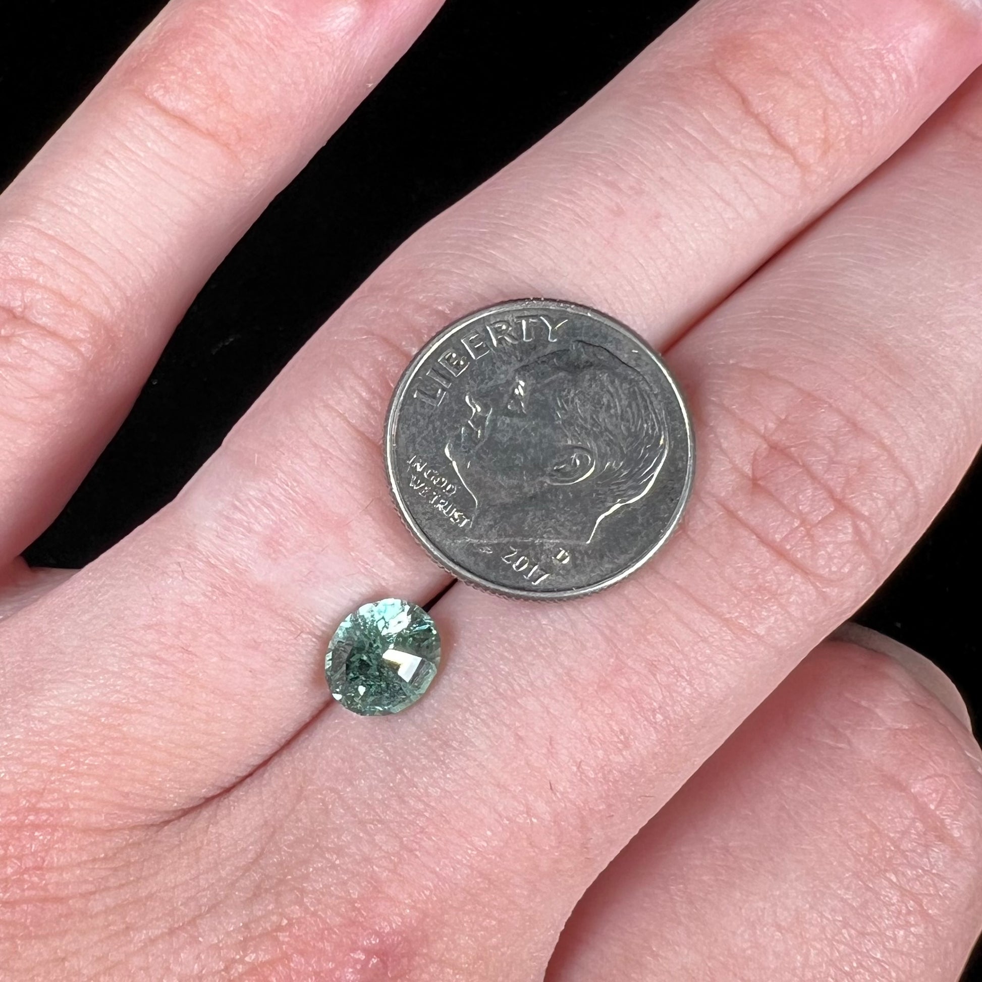 A loose, faceted modified oval cut mint green tourmaline gemstone.