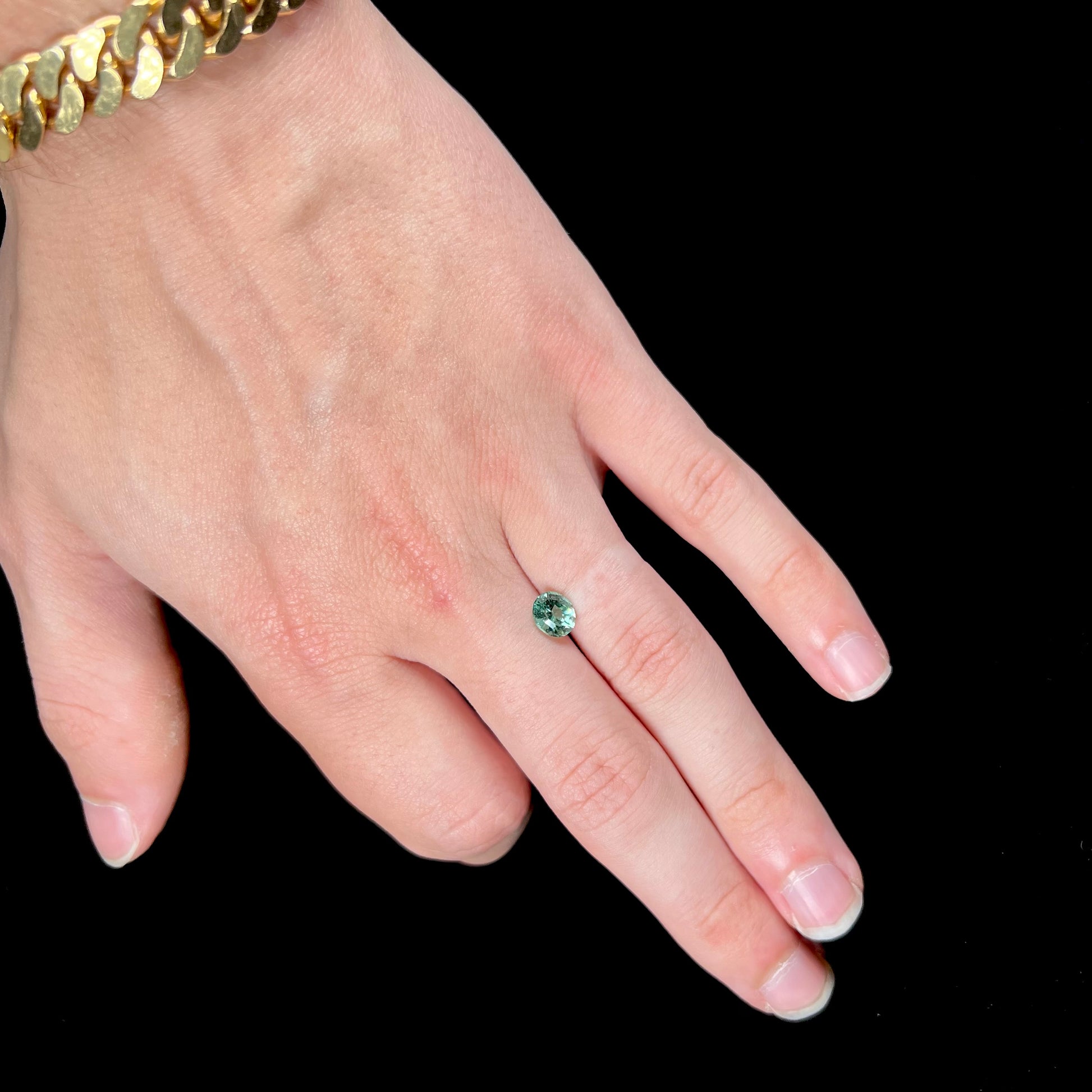 A loose, faceted modified oval cut mint green tourmaline gemstone.