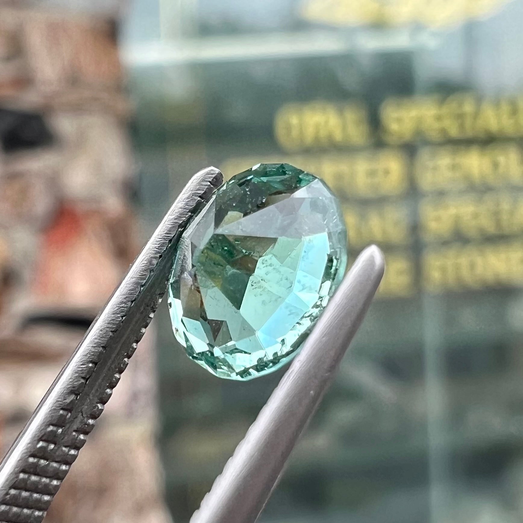 A loose, faceted modified oval cut mint green tourmaline gemstone.