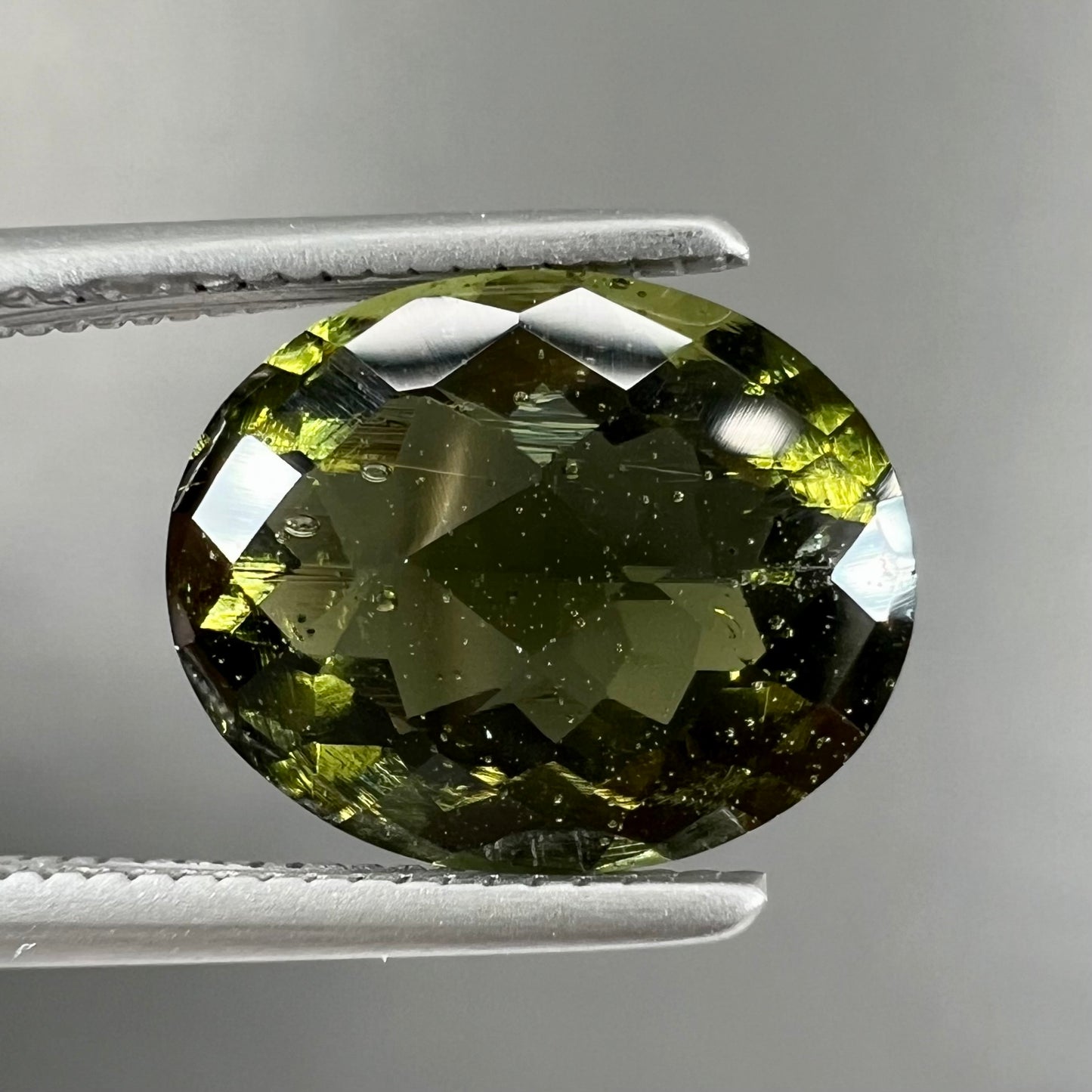 A loose, faceted oval checkerboard moldavite gemstone from the Czech Republic.