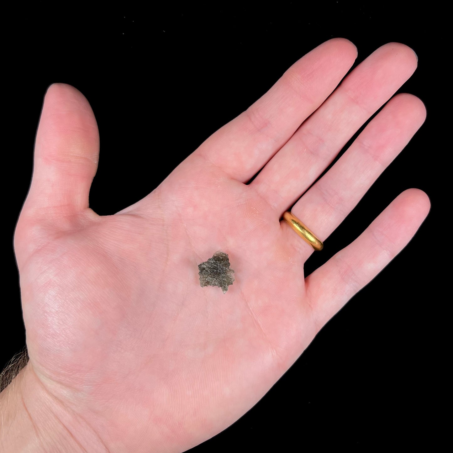 A natural, rough moldavite crystal.  The stone is green color and transluscent.