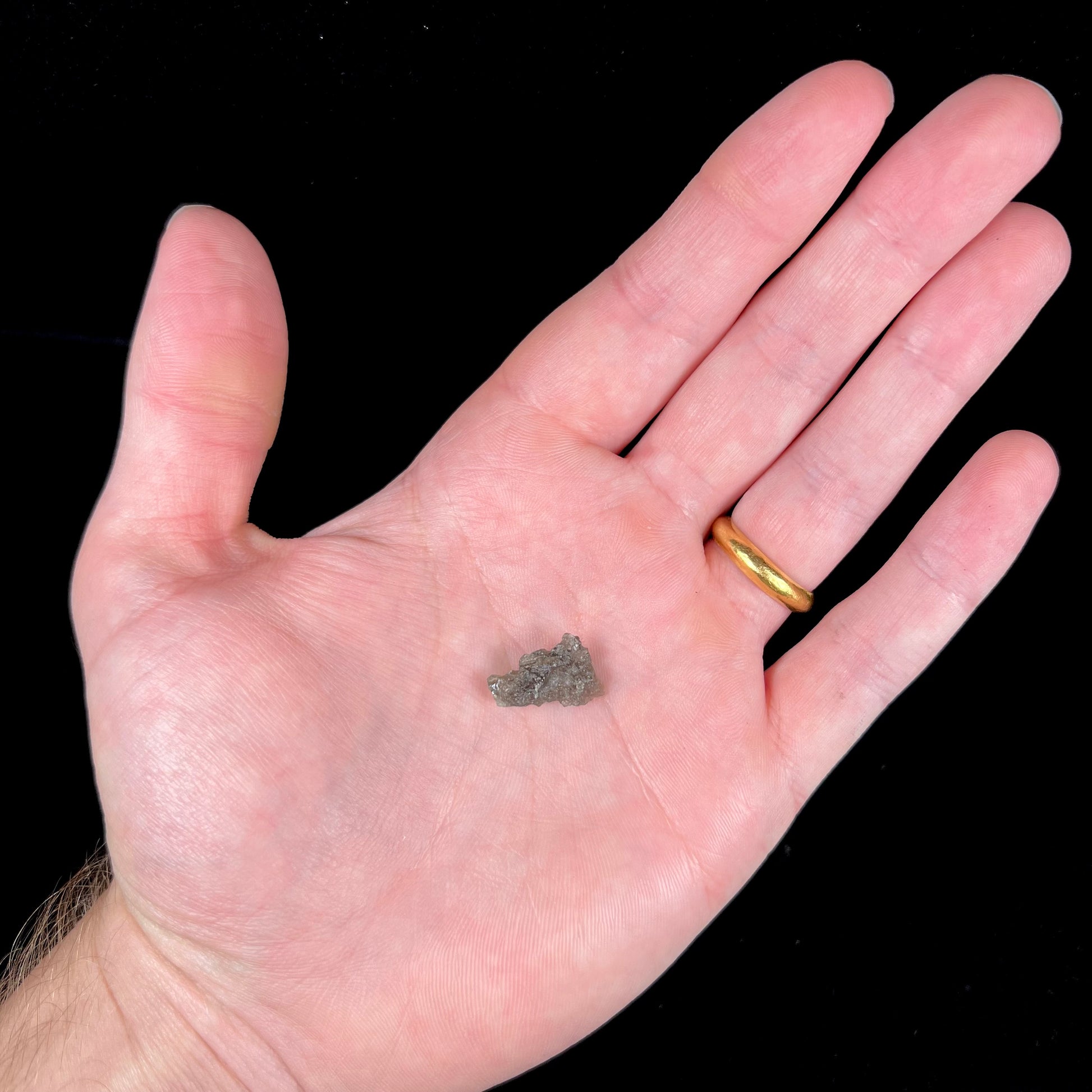 A natural, rough moldavite crystal.  The stone is green color and transluscent.