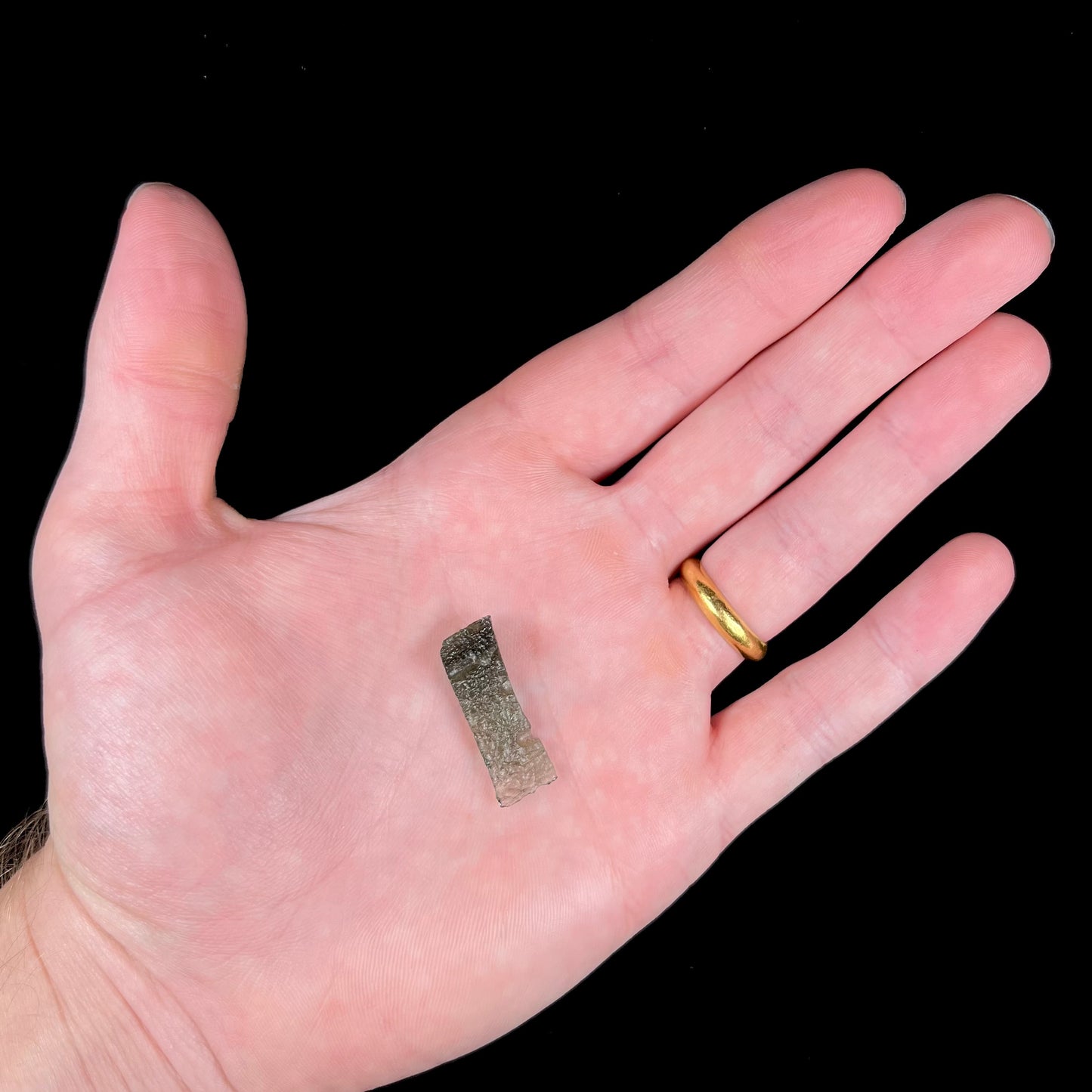 A natural, rough moldavite crystal.  The stone is shaped like the Nike Swoosh logo.