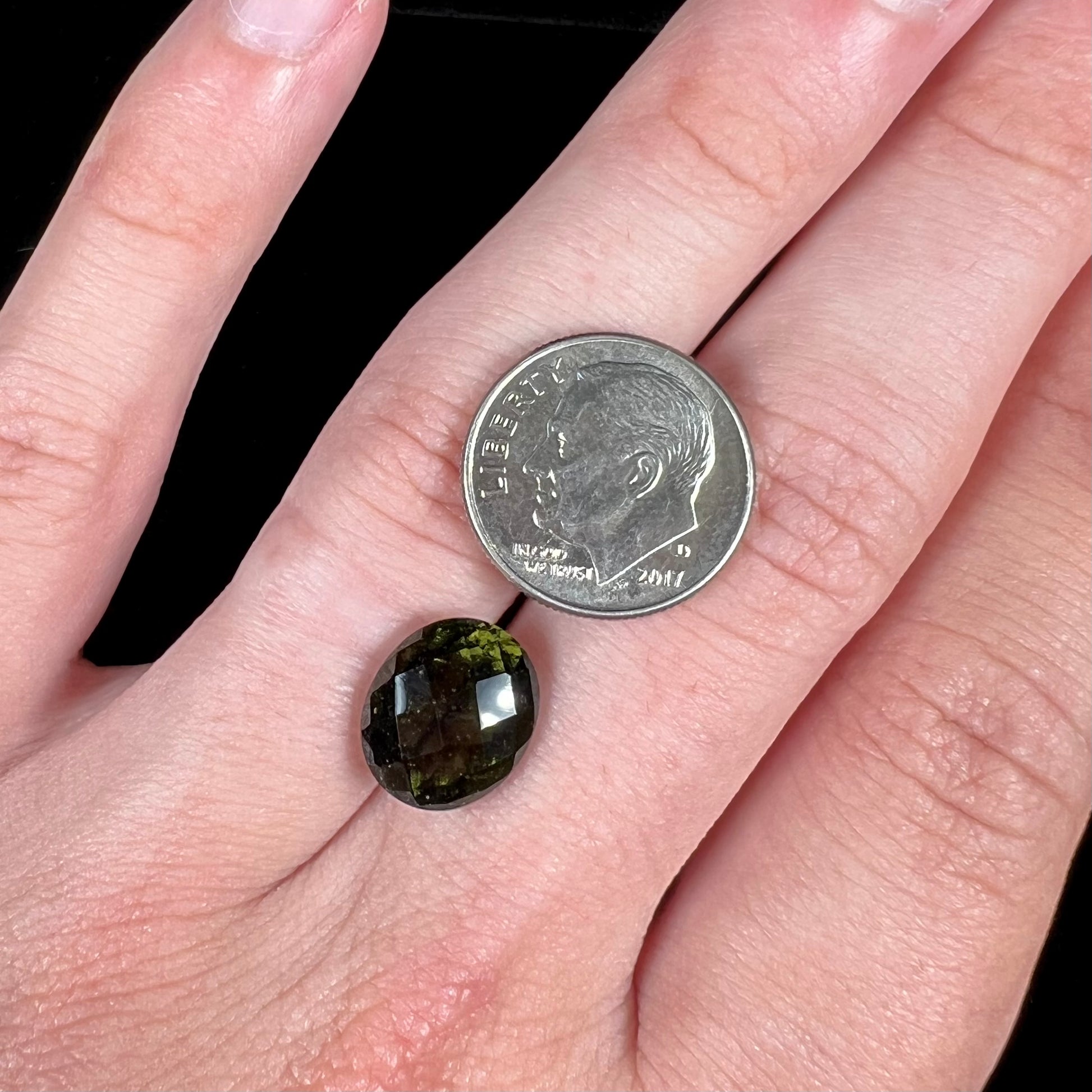 A loose, faceted oval cut natural moldavite gemstone.