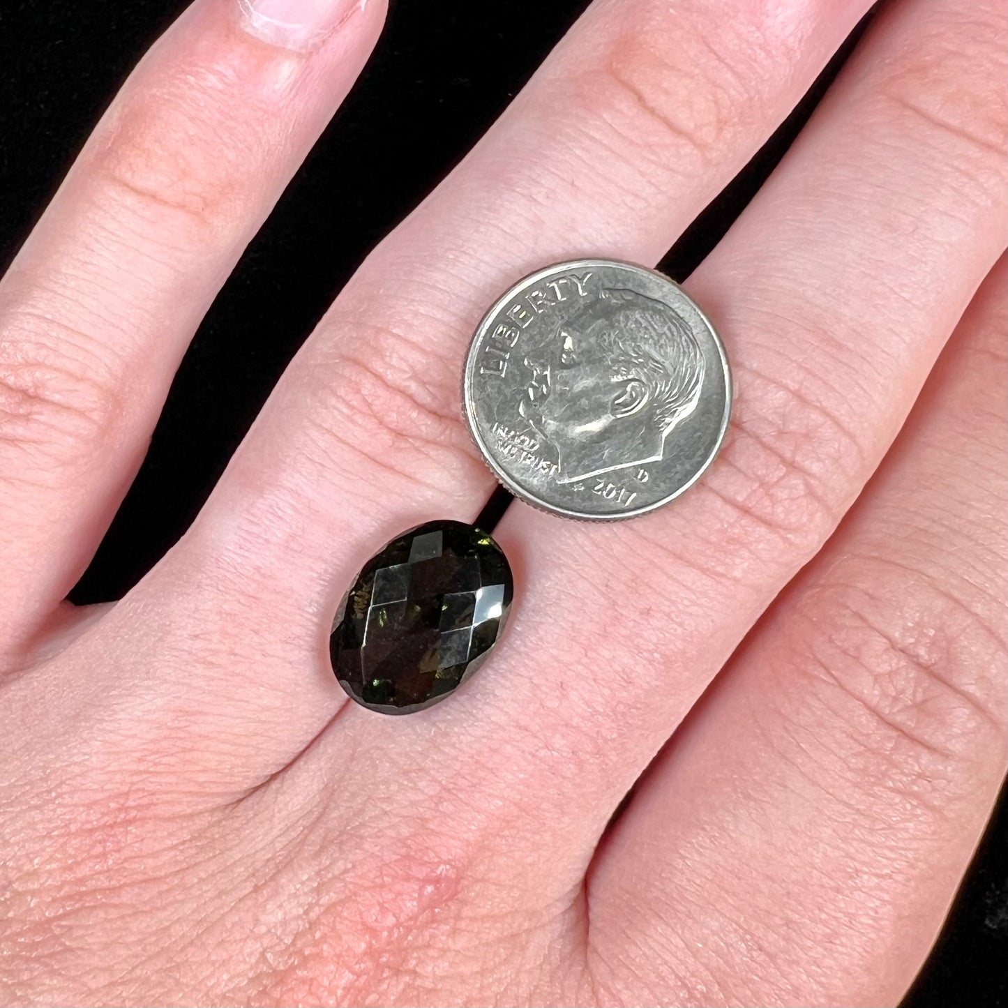 A faceted oval cut natural moldavite gemstone.