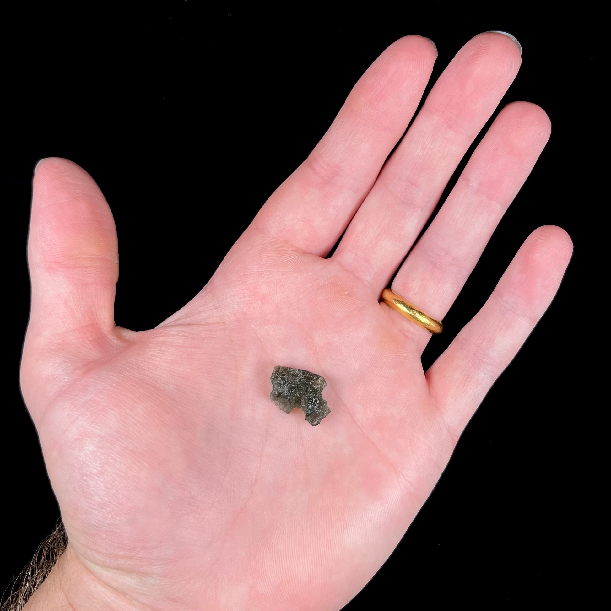 A natural, rough moldavite crystal.  The stone is green color and transluscent.