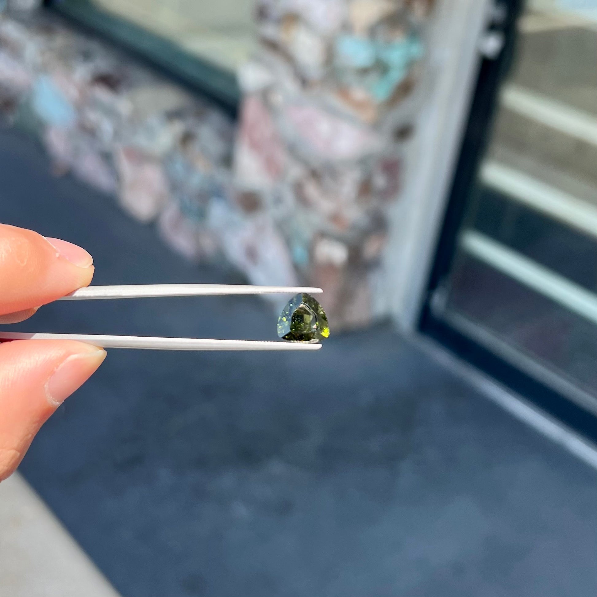 A natural, trillion cut moldavite gemstone.