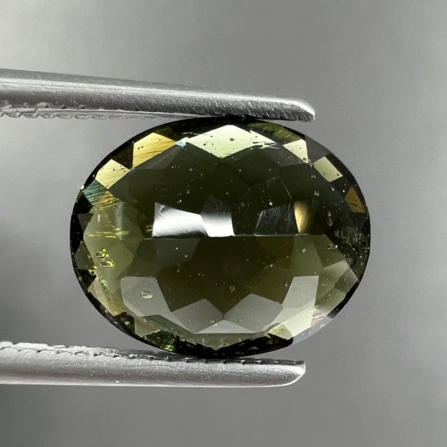 A loose, faceted oval checkerboard moldavite gemstone from the Czech Republic.