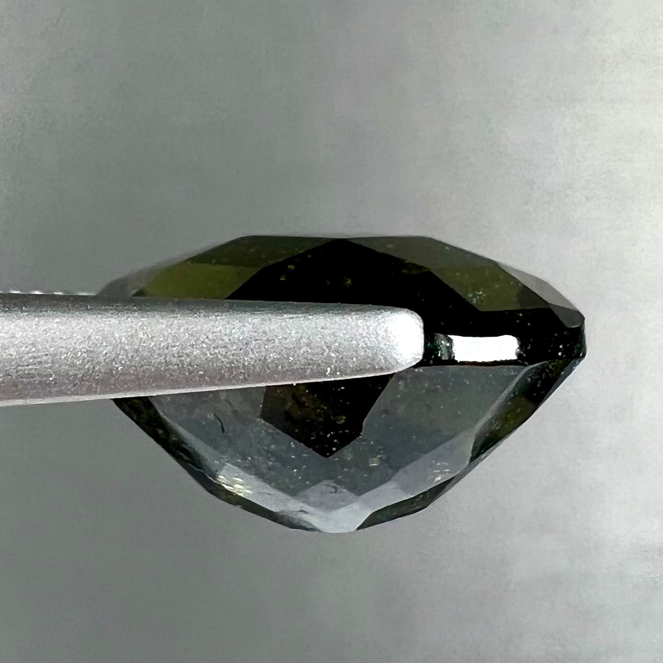 A loose, faceted oval cut natural moldavite gemstone.