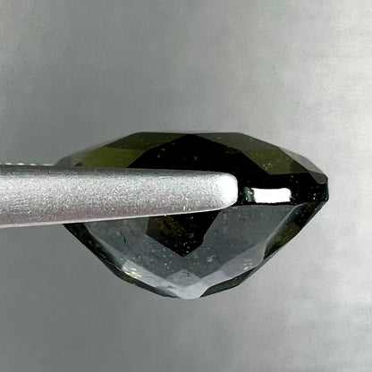A loose, faceted oval cut natural moldavite gemstone.
