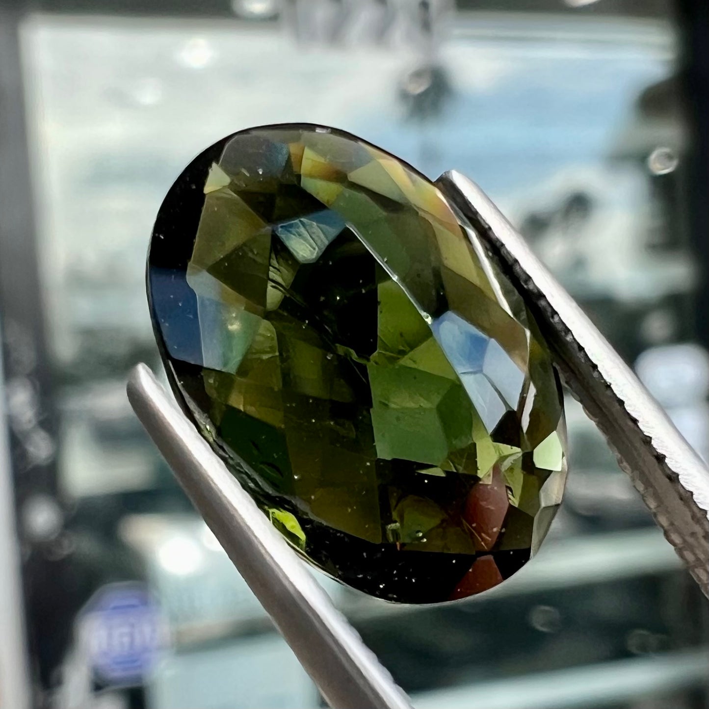 A faceted oval cut natural moldavite gemstone.