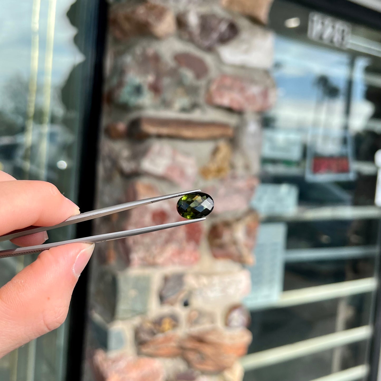 A faceted oval cut natural moldavite gemstone.