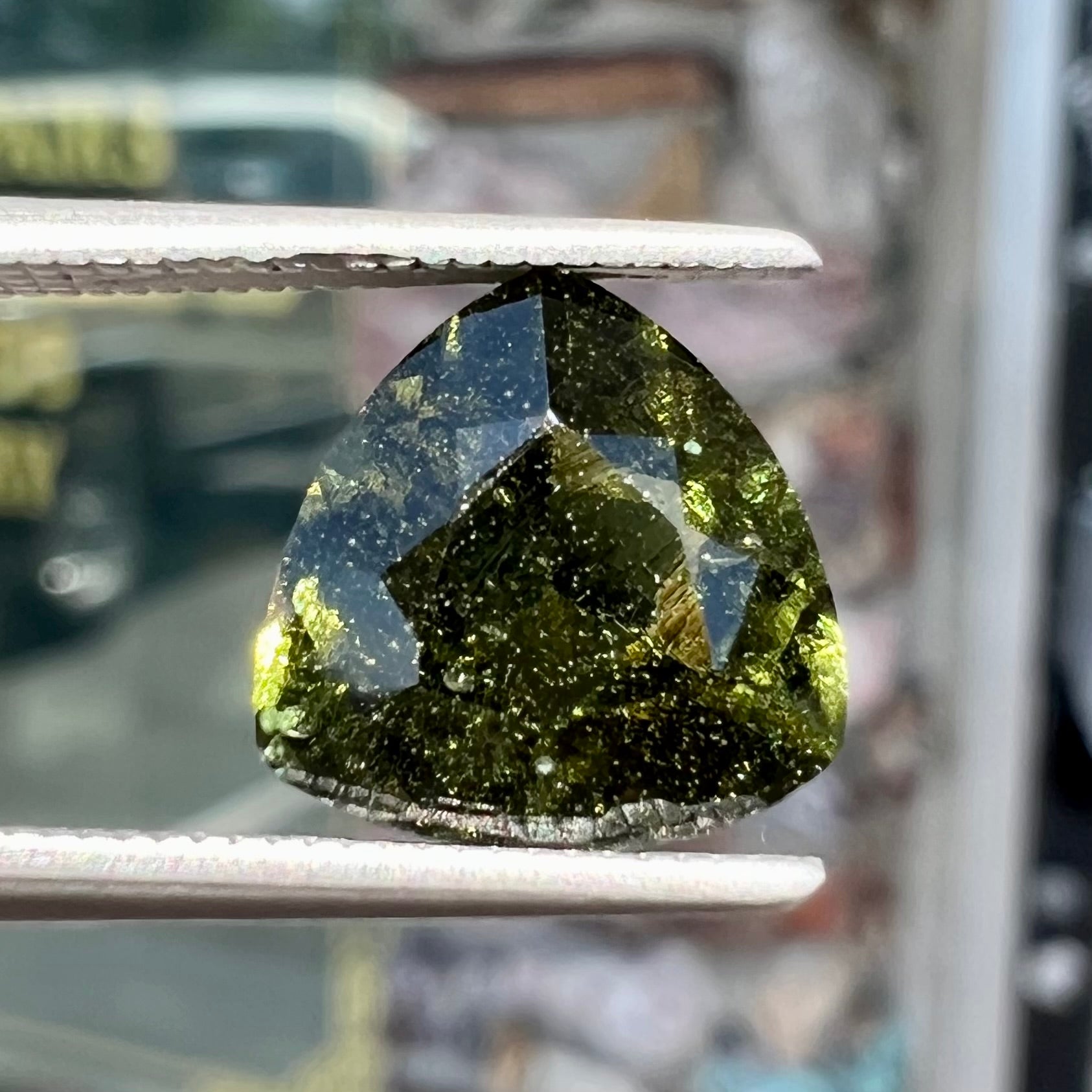 A trillion cut natural moldavite gemstone.  The stone shows inclusions.