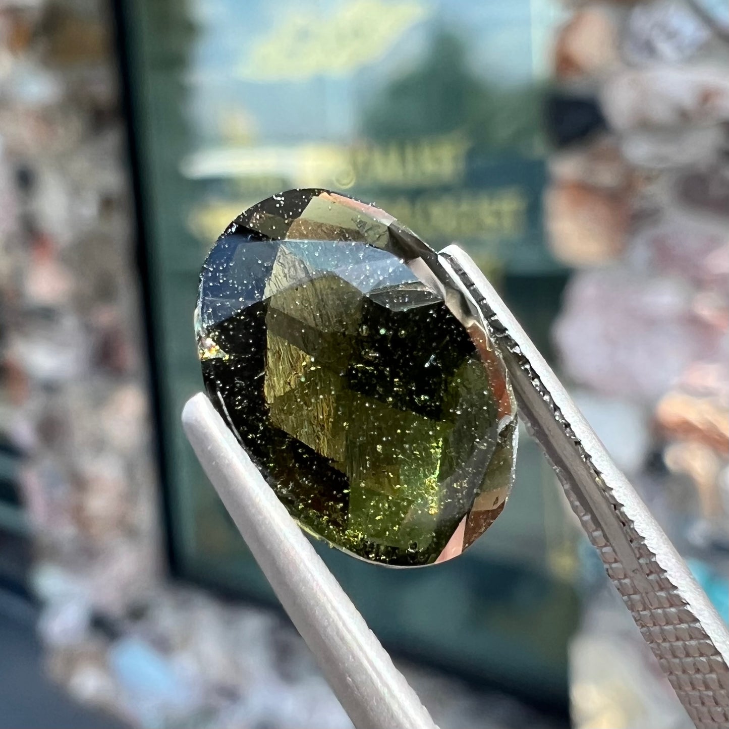 A loose, faceted oval cut natural moldavite gemstone.