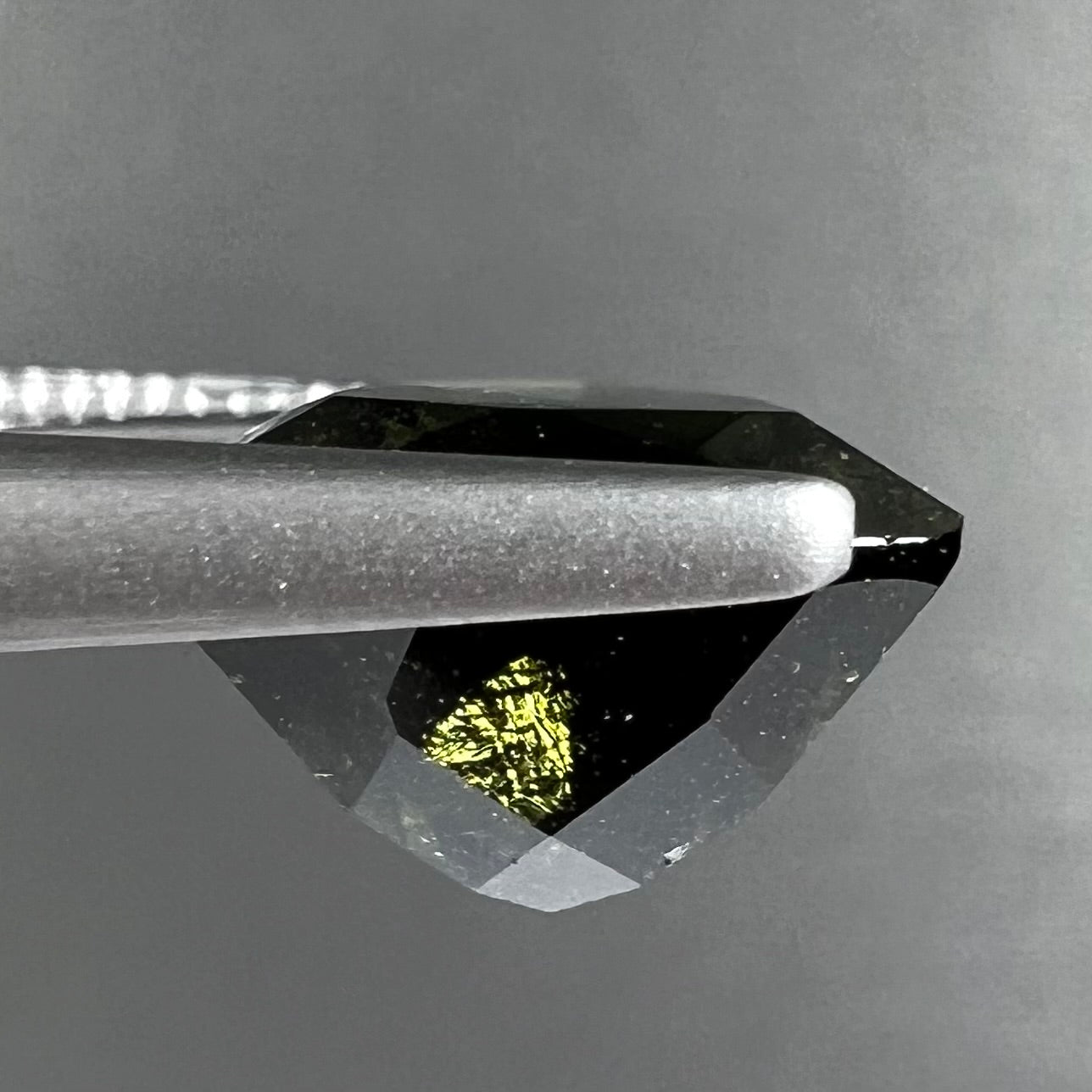 A natural, trillion cut moldavite gemstone.