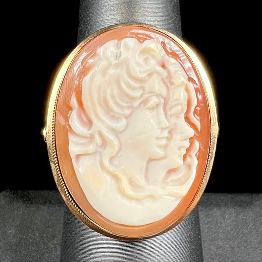 A ladies' vintage cameo solitaire ring in yellow gold.  The cameo is carved from shell and depicts the side profile of two womens' faces.