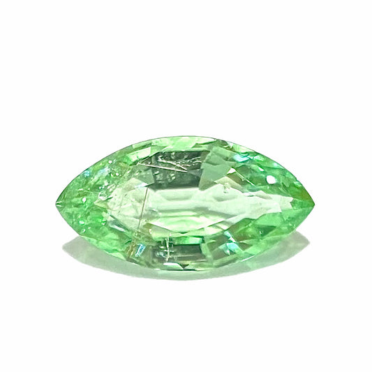 A faceted marquise cut electric green tourmaline gemstone.  The stone has an eye-visible rutile needle inclusion.
