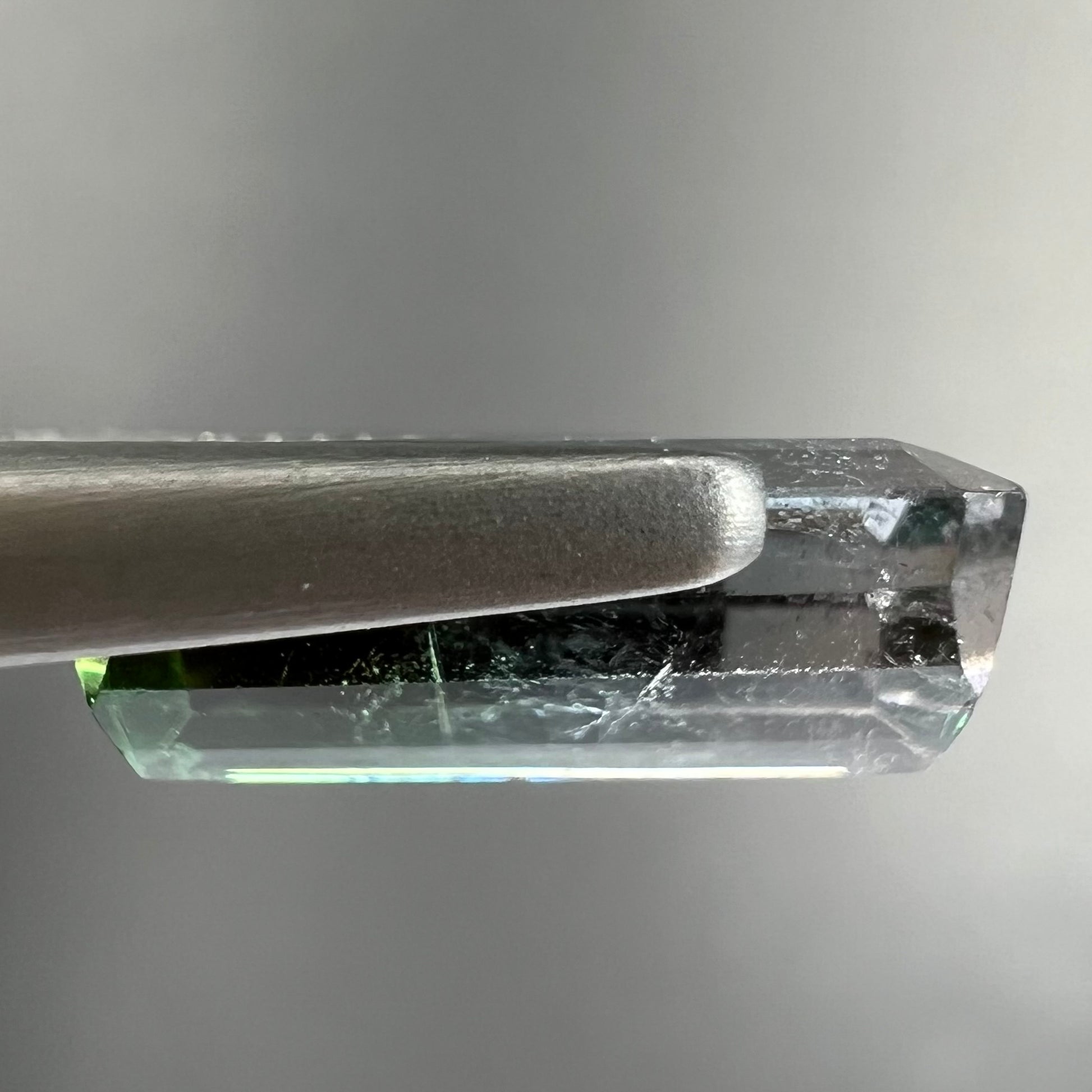 A loose, emerald cut tricolor tourmaline gemstone.  The stone transitions from green to blue to white colors.