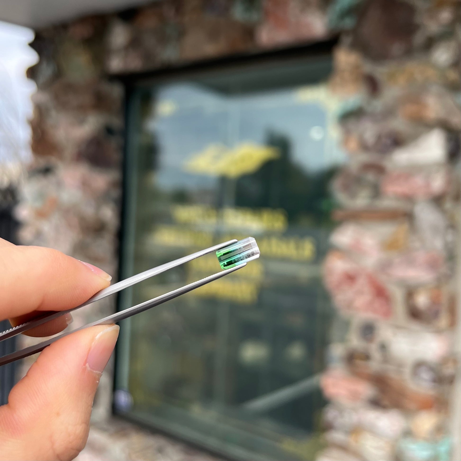 A loose, emerald cut tricolor tourmaline gemstone.  The stone transitions from green to blue to white colors.
