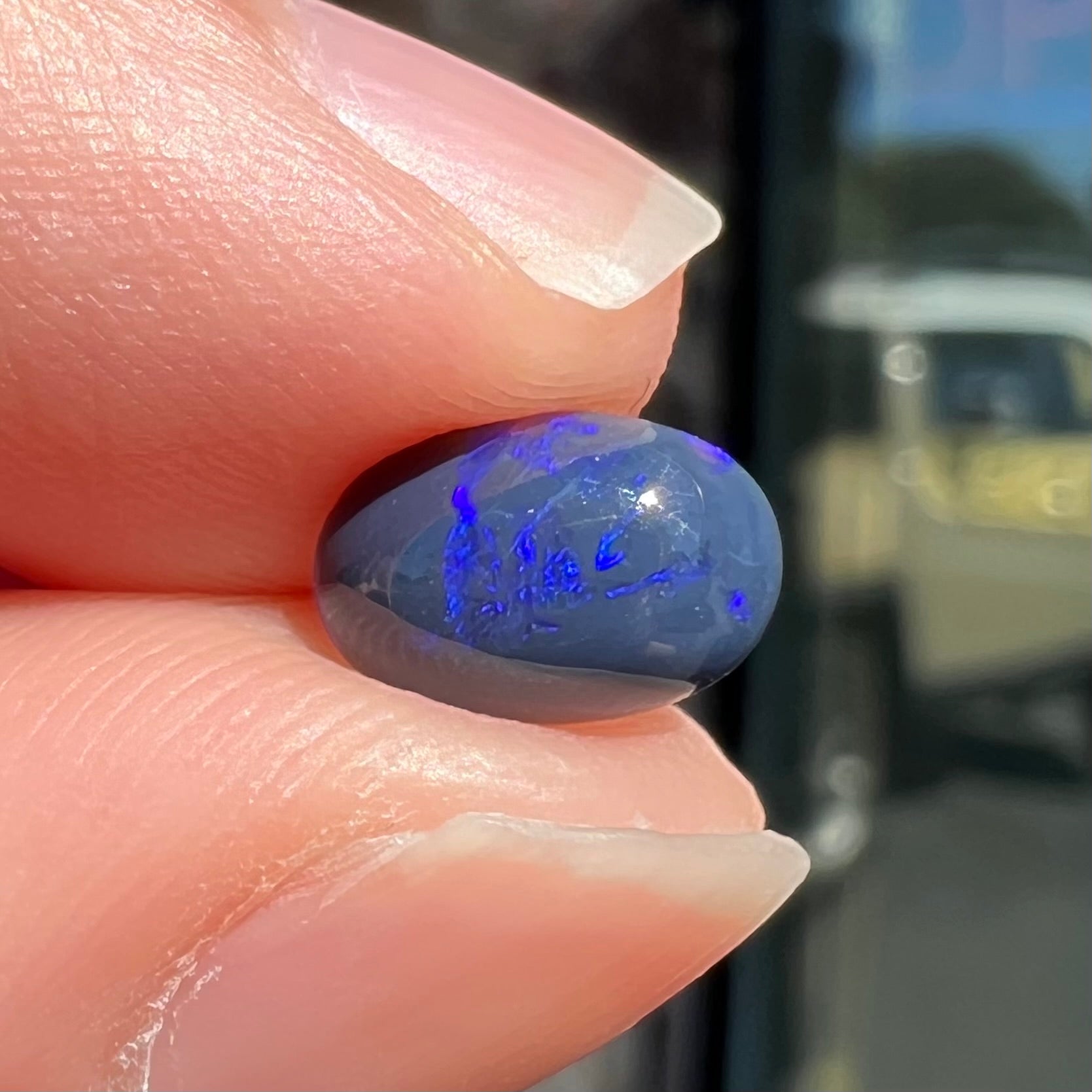 A loose, oval cabochon cut black opal stone from Lightning Ridge, Australia.  The opal has an N2 body tone.