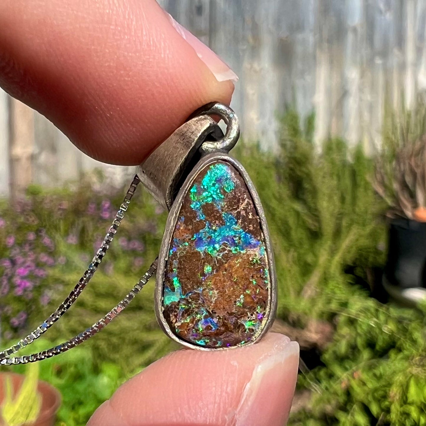 A handmade, satin finish sterling silver pendant set with a drop shaped boulder opal stone.