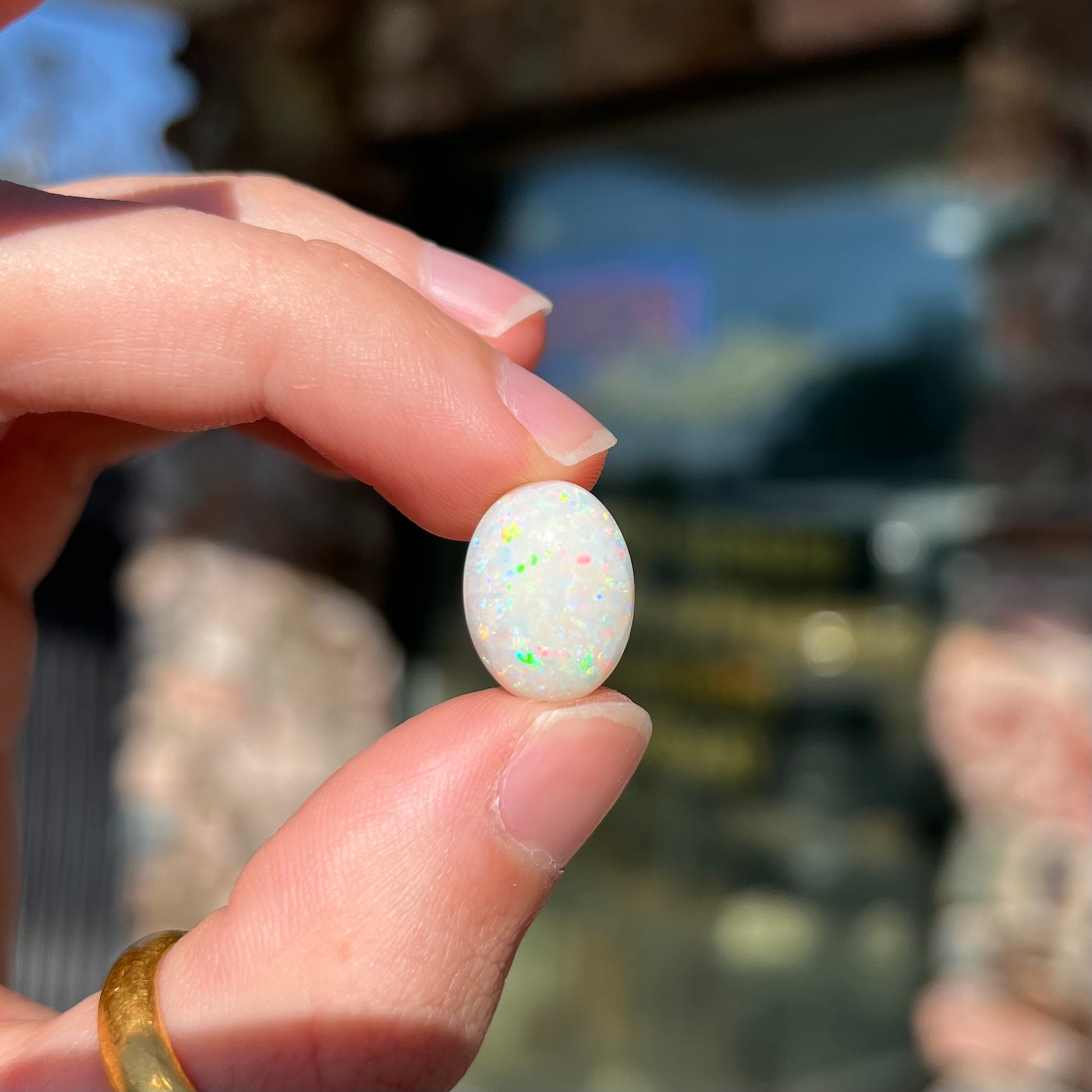 An oval cabochon cut white opal.  The opal has an eye-visible natural fissure inclusion.